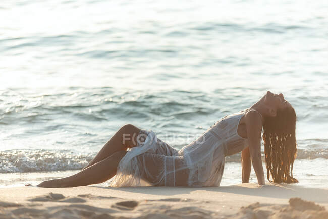 Donna felice sdraiata vicino al mare ondeggiante — Foto stock