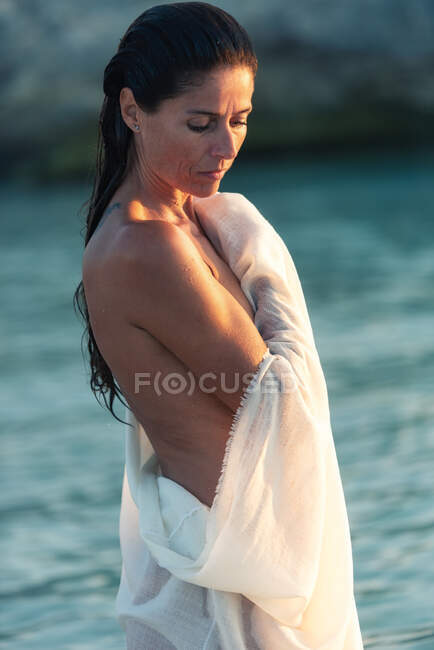 Mujer desnuda entrando en el agua del mar - foto de stock