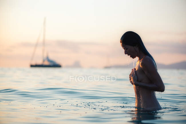 Mulher nua no mar durante o pôr do sol — Fotografia de Stock