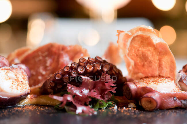 Proches tentacules délicieux de calmar servi avec des épices sur fond flou de restaurant de fantaisie — Photo de stock