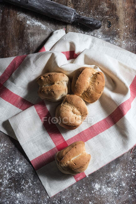 Вид зверху хліба зі свіжого хліба, розміщеного на кухонному рушнику на сільському дерев'яному столі, покритому борошном у пекарні — стокове фото