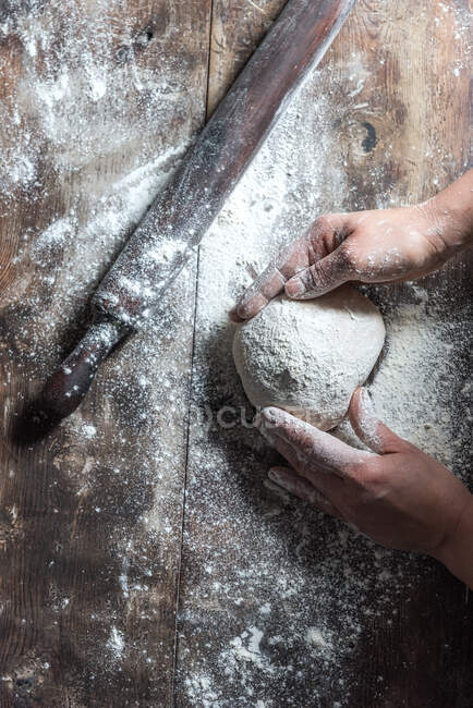Unbekannter knetet Teig mit Mehl auf Tisch bei Bäckereiarbeit — Stockfoto