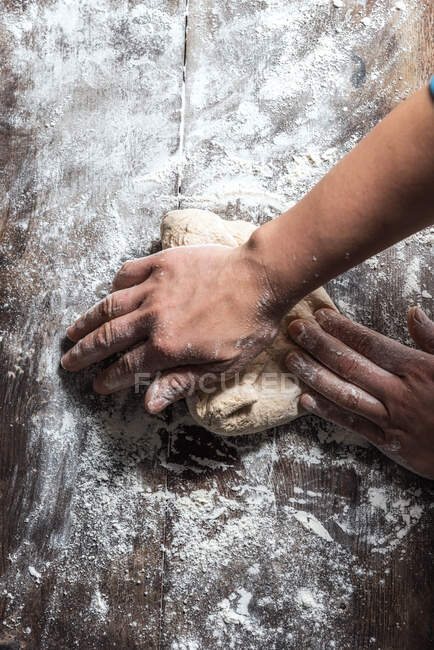 Unrecognizable person kneading dough with flour on table while working in bakery — Stock Photo