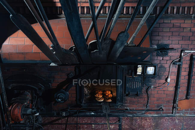 Conjunto de pães frescos colocados dentro do forno de tijolo quente na padaria profissional — Fotografia de Stock