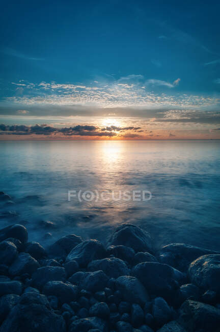 Vista pitoresca do céu nublado do pôr-do-sol sobre a água do mar pacífica e a costa pedregosa de Cap des Falco em Ibiza, Espanha — Fotografia de Stock