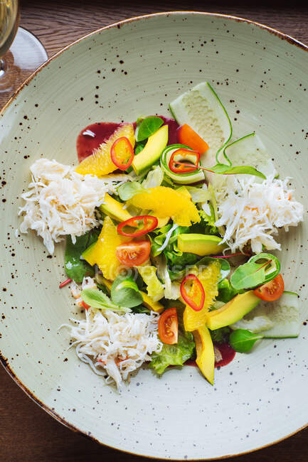 Vista superior de la apetitosa ensalada colorida saludable con verduras y frutas frescas y pollo rallado servido en un tazón - foto de stock