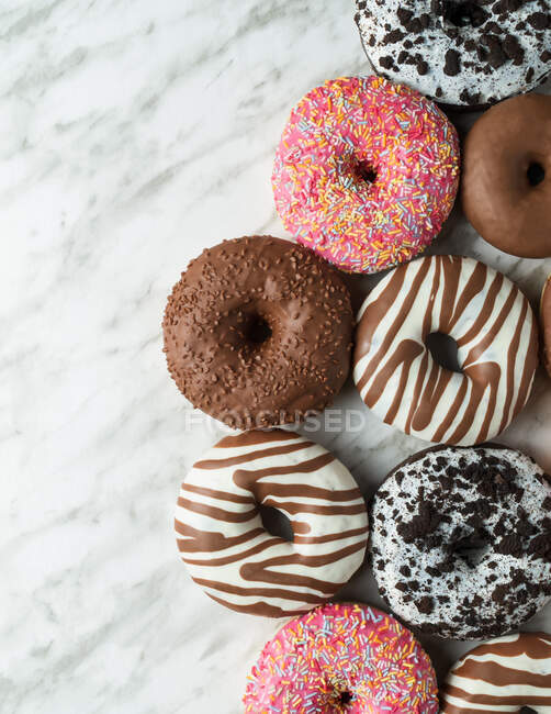 Draufsicht auf traditionelle süße Donuts mit Sahnehäubchen auf heller Marmoroberfläche — Stockfoto