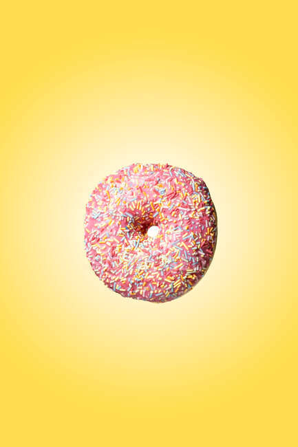 Pink sweet doughnut floating on yellow background — Stock Photo