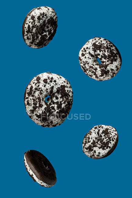Donuts de chocolate doce branco e preto flutuando no fundo azul — Fotografia de Stock