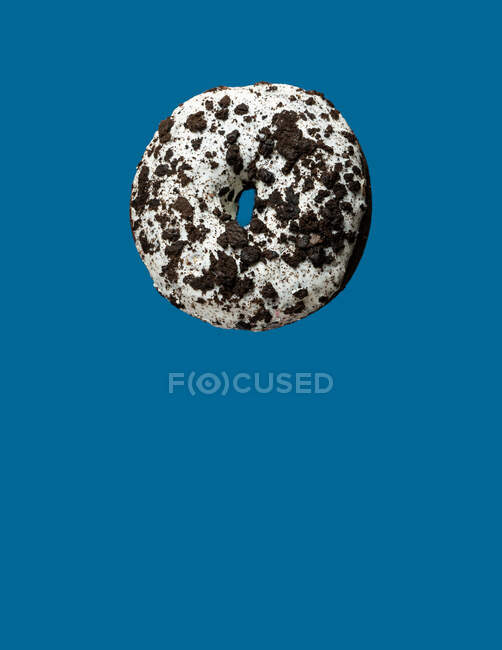 Пончик из белого и черного шоколада, плавающий на синем фоне — стоковое фото