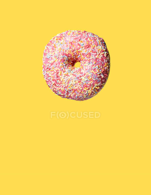 Pink sweet donghnut floating on yellow background — стоковое фото