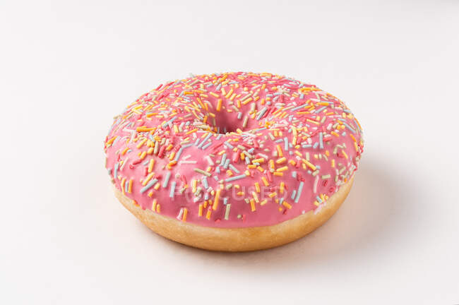 Цілий смачний солодкий посипаний рожевий глазурований пончик на білому тлі — стокове фото