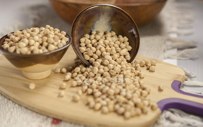 Metal bowls with uncooked fresh chickpea placed on wooden cutting board on table in kitchen — Stock Photo