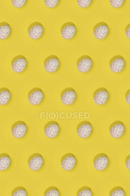 Padrão de Páscoa sem costura com ovos decorados coloridos dispostos em linhas no fundo amarelo — Fotografia de Stock