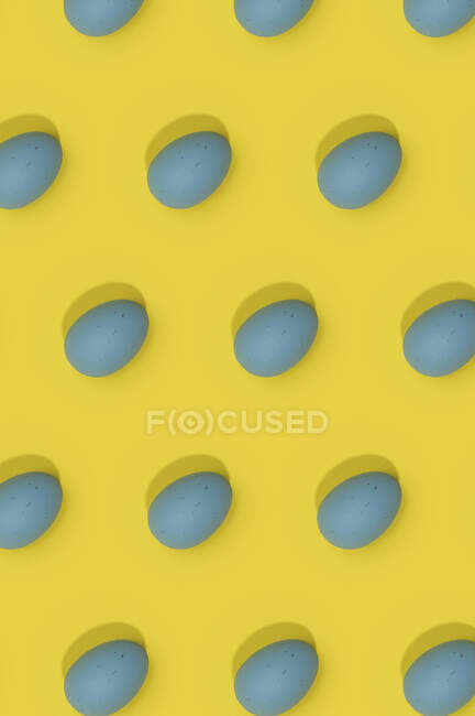 Бесшовный пасхальный узор с цветными украшенными яйцами, расположенными рядами на желтом фоне — стоковое фото