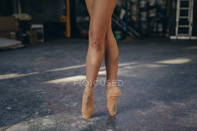 Обрізане зображення танцівниці балету в точках з синцем на нозі, що стоїть на топі під час виконання класичних вправ під час тренувань в студії — стокове фото
