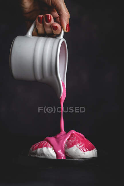 Unrecognizable crop woman hand with white jar pouring pink strawberry syrup on homemade white Zefir traditional russian dessert with mint on black background — Stock Photo