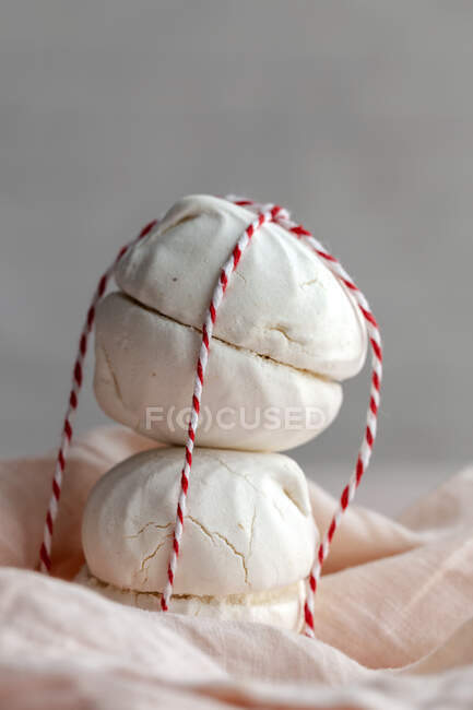 Hausgemachtes weißes Zefir-Dessert, das an einem kleinen Seil auf rosa Hintergrund gehalten wird — Stockfoto