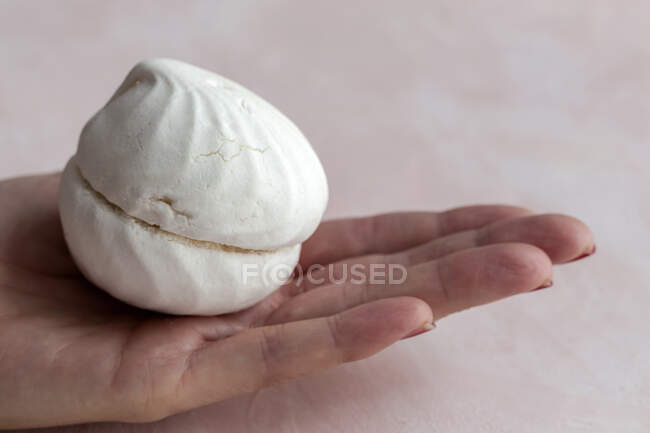 Cropped unrecognizable person holding a homemade white Zefir traditional russian dessert on pink background — Stock Photo