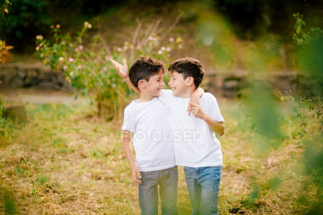 Glückliche Zwillingsjungen, die sich im Park umarmen und anschauen — Stockfoto