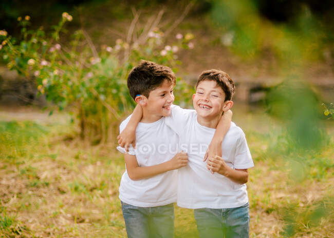 Glückliche Zwillingsjungs umarmen sich und schauen in die Kamera im Park — Stockfoto