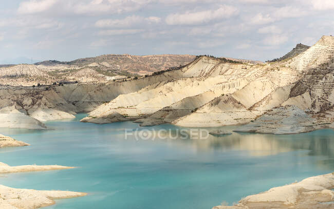 Reservatório de água limpa localizado entre a costa com grama seca e montanha áspera em dia nublado em Algeciras, Espanha — Fotografia de Stock