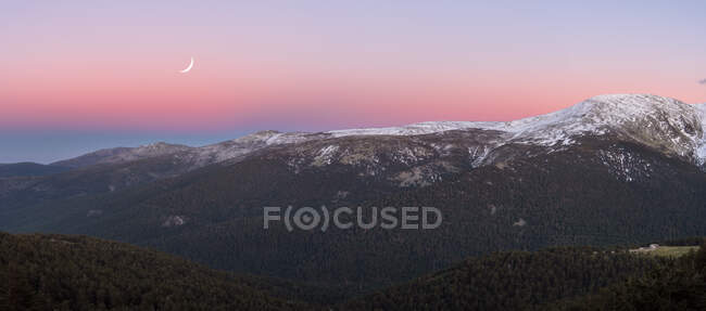 Atemberaubender Weitwinkelblick auf schneebedecktes Gebirge vor Abendhimmel mit weißen Wolken und Mond in der Natur — Stockfoto
