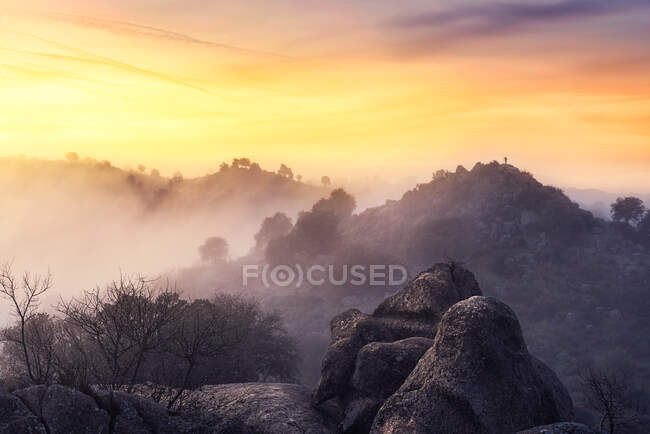 Catena montuosa ruvida situata contro il luminoso cielo all'alba in una mattina nebbiosa nella natura — Foto stock