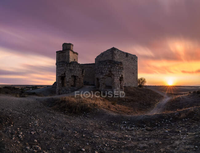 Visitando o castelo medieval arruinado contra o céu nublado do pôr-do-sol no campo em Toledo — Fotografia de Stock