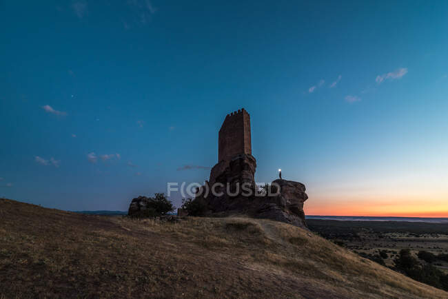 Dal basso turista irriconoscibile esplorare il castello medievale in rovina contro il bellissimo cielo del tramonto — Foto stock