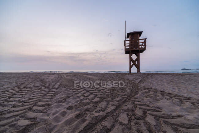 Torre salva-vidas de madeira localizada na costa arenosa contra o céu pôr do sol no resort — Fotografia de Stock