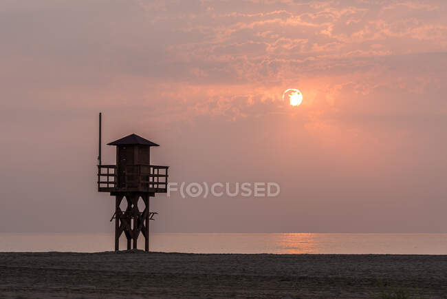 Torre salvavita in legno situata sulla riva sabbiosa contro il cielo del tramonto sul resort — Foto stock
