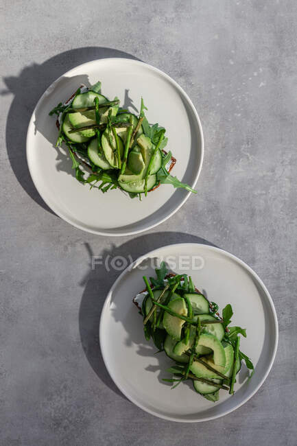 Delicious toasts with fresh vegetables and herbs on plates — Stock Photo