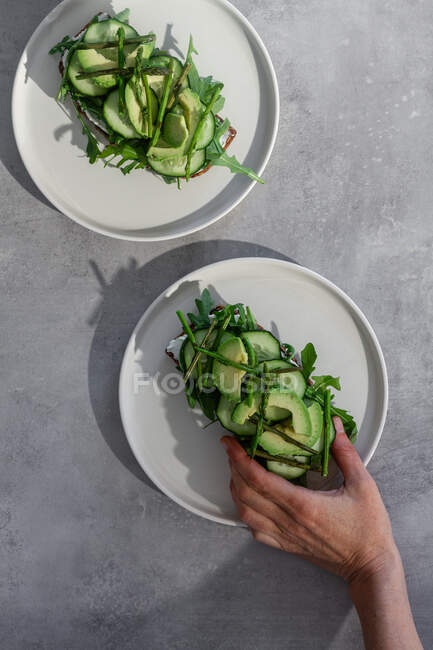 Person hält Toast mit grünem Gemüse — Stockfoto