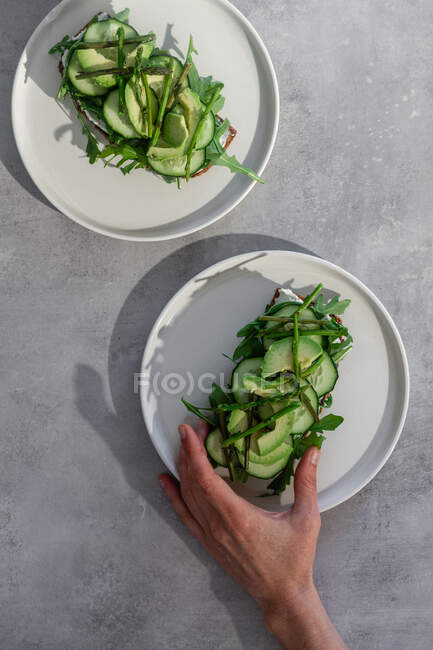 Person holding toast with green vegetables — Stock Photo