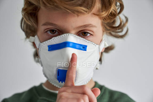 Хлопчик-блондин, якому близько 8 років, одягнений у респіратор, щоб співзаразити себе вірусом. — стокове фото