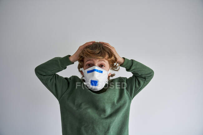 Blonder Junge, etwa 8 Jahre alt, trägt eine Atemschutzmaske, um sich mit einem Virus zu infizieren — Stockfoto