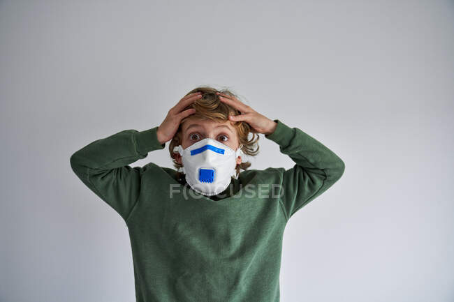 Blonder Junge, etwa 8 Jahre alt, trägt eine Atemschutzmaske, um sich mit einem Virus zu infizieren — Stockfoto