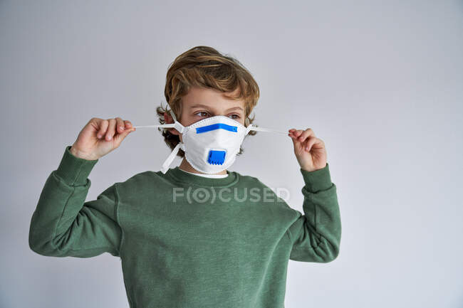 Блондин, около 8 лет, носит респиратор, чтобы заразить себя вирусом. — стоковое фото