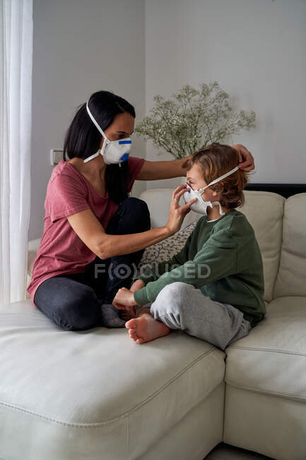 Мама поставила респиратор для своего ребенка, чтобы избежать возможной инфекции — стоковое фото