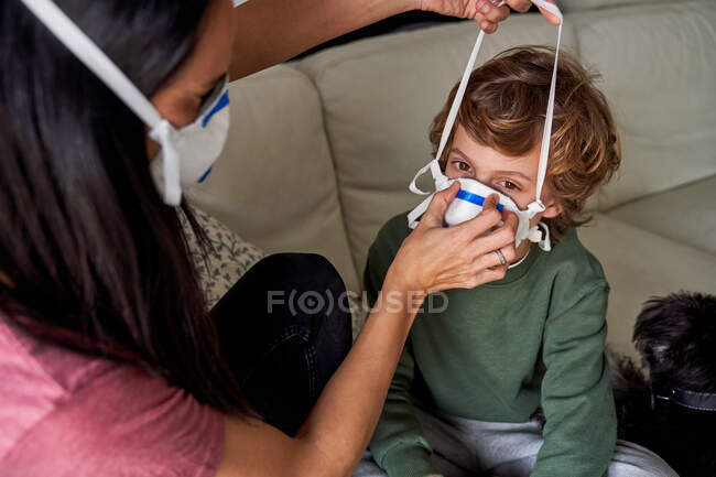 Mãe colocando um respirador para seu filho para evitar possíveis infecções — Fotografia de Stock