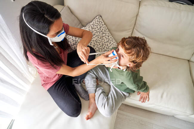 Mãe colocando um respirador para seu filho para evitar possíveis infecções — Fotografia de Stock