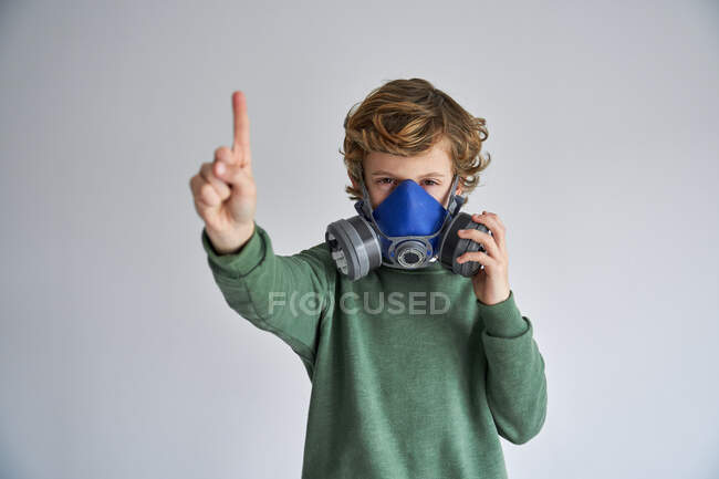 Blonder Junge, der eine Atemmaske trägt und einen Finger zeigt — Stockfoto