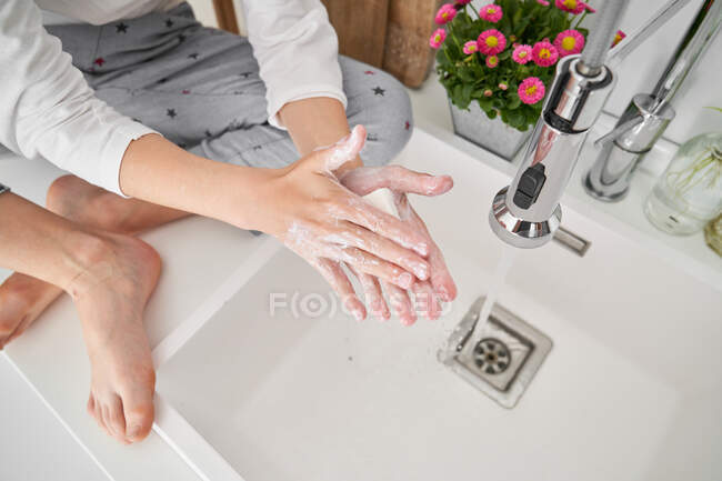 Abgeschnittenes Bild eines Kindes, das sich in der Spüle die Hände wäscht, um eine Infektion zu verhindern — Stockfoto
