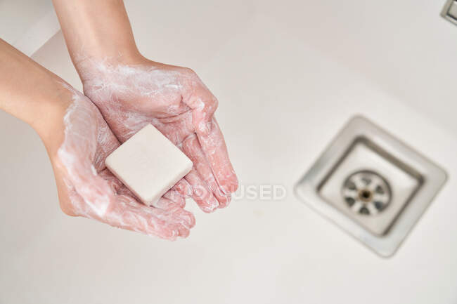 Imagen recortada de niño lavándose las manos en el fregadero de la cocina para evitar cualquier infección - foto de stock
