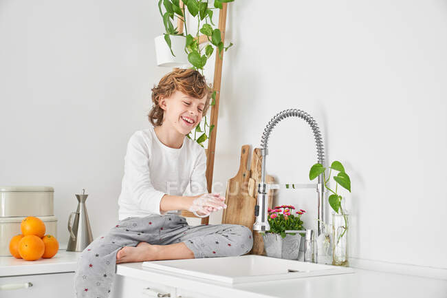 Blond child washing his hands in the kitchen sink to prevent any infection — Stock Photo