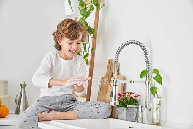 Bambino biondo che si lava le mani nel lavandino della cucina per prevenire qualsiasi infezione — Foto stock