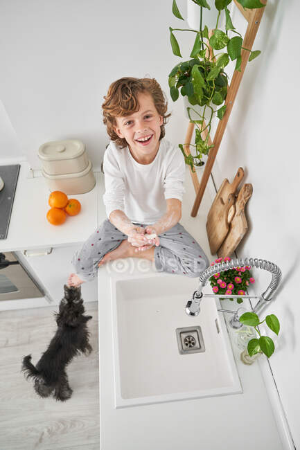 Blond child washing his hands in the kitchen sink to prevent any infection — Stock Photo