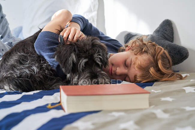 Blonder Junge liegt mit Hund auf dem Bett — Stockfoto