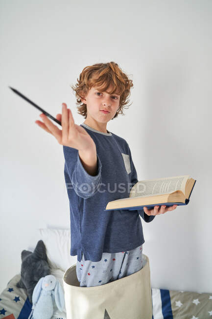 Niño rubio en pijama con un libro jugando a la investigación - foto de stock